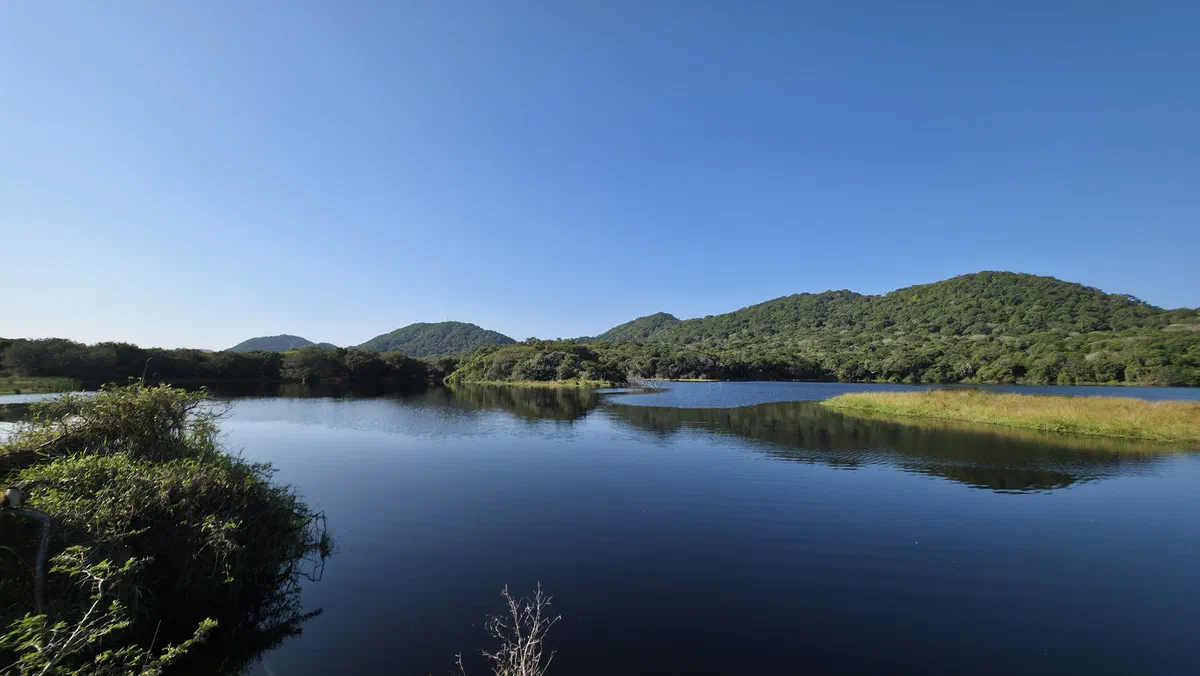 Lake St Lucia below forested hills under a clear blue sky